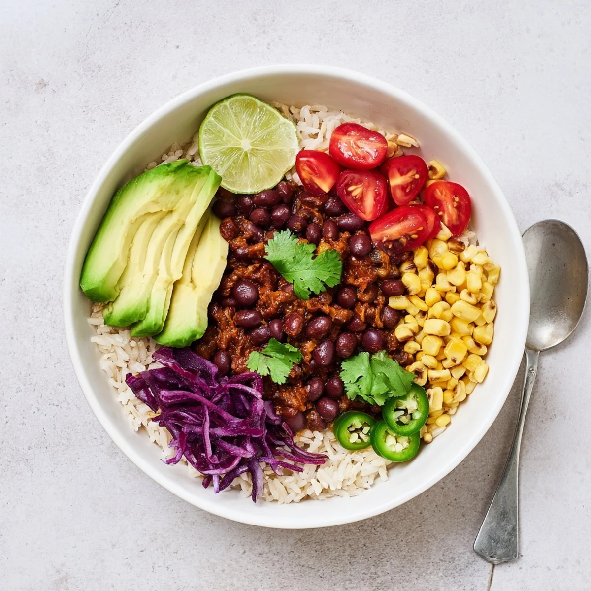 Colorful black bean and rice bowl garnished with shredded cabbage and lime wedges