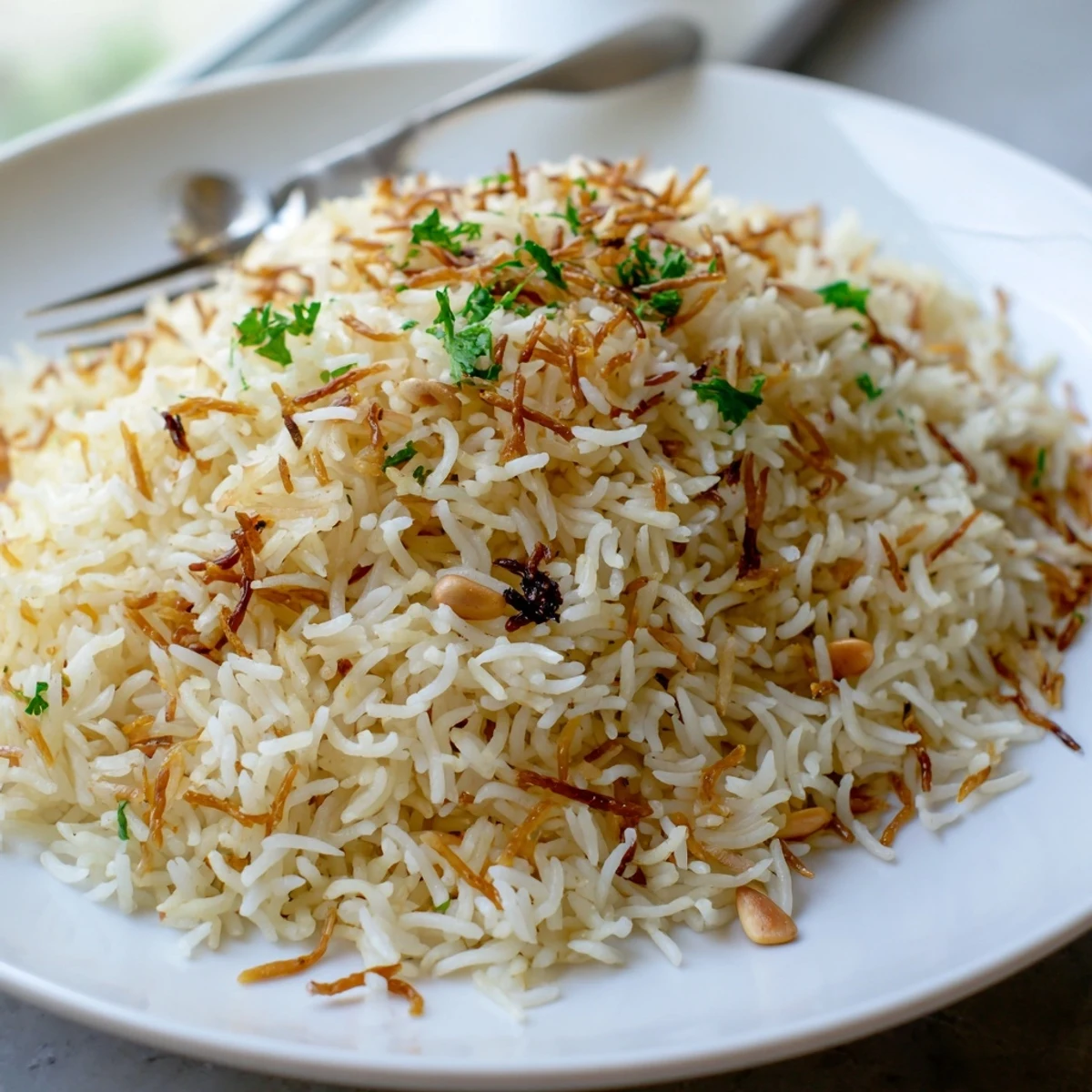 Close-up of fluffy Lebanese Rice garnished with toasted pine nuts and herbs