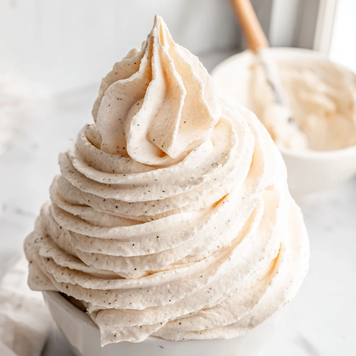 Creamy Italian Meringue Buttercream piped in swooping rosettes on a golden layer cake