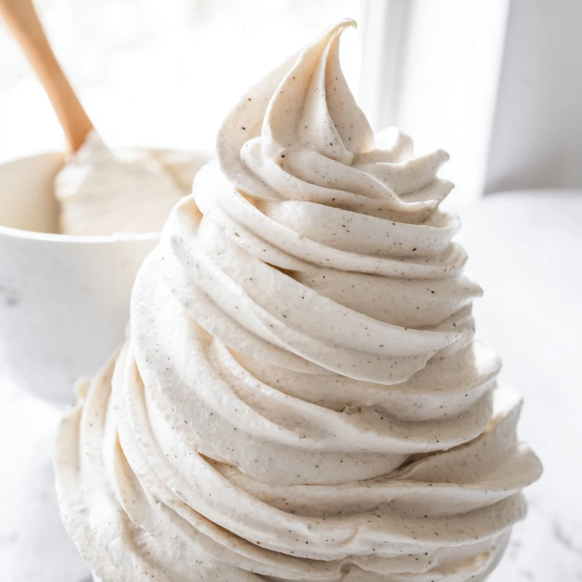 Glossy Italian Meringue Buttercream spread thick over a three-layer vanilla celebration cake