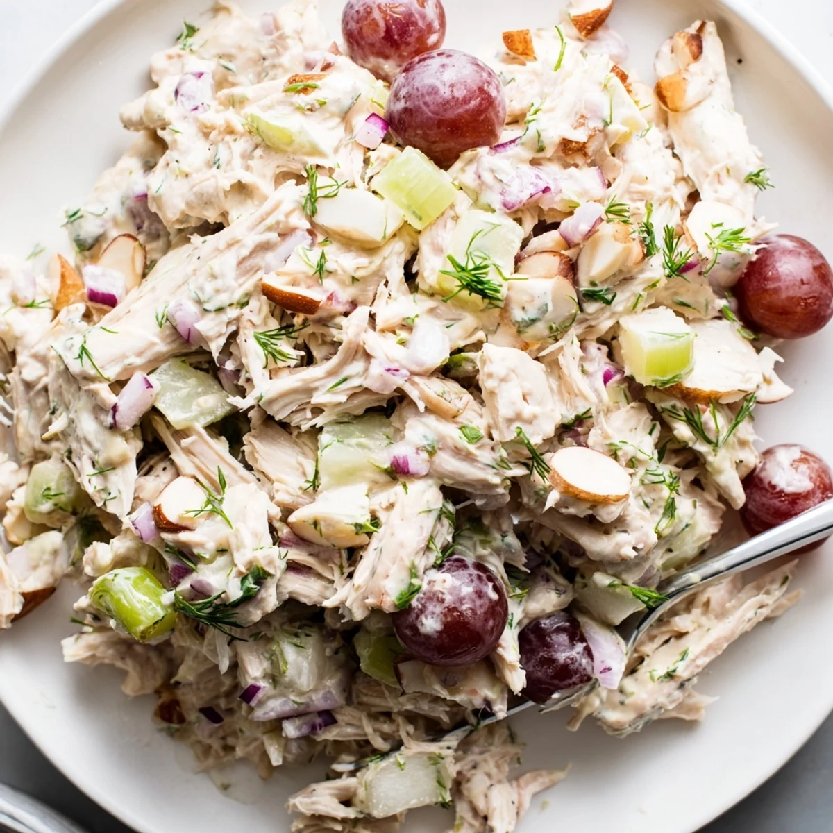 Vibrant vegan chicken salad scooped over leafy greens with juicy red grapes and almonds