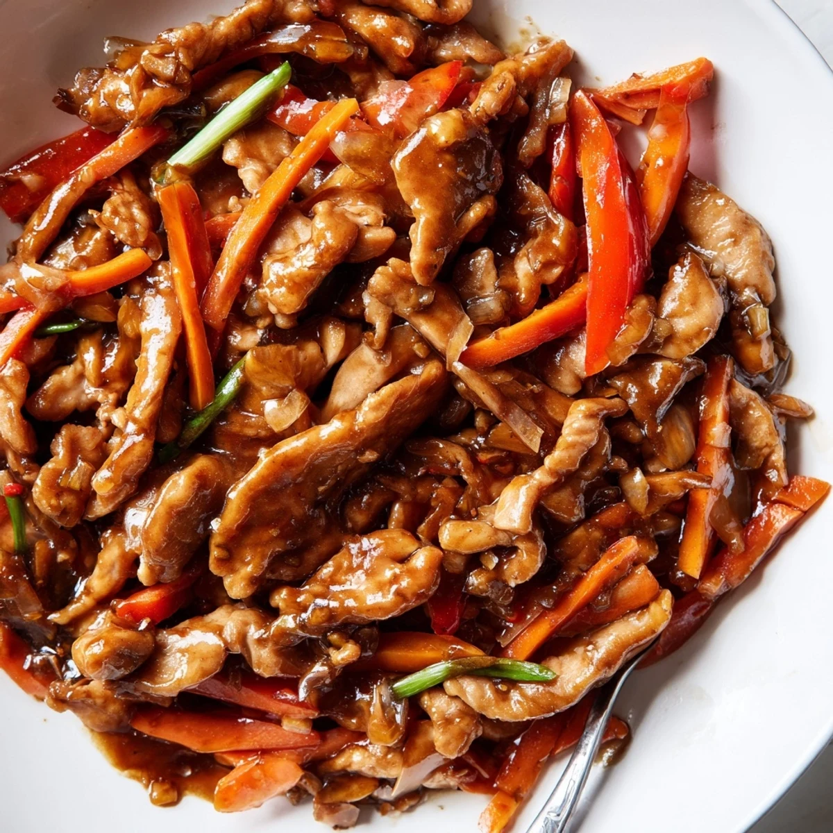 Glossy stir fried Chinese garlic chicken with vibrant bell peppers and steamed white rice