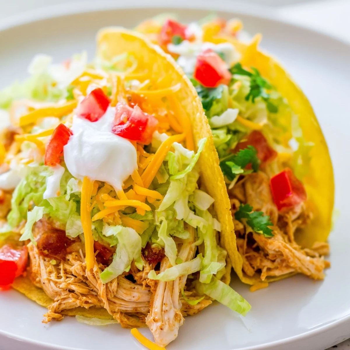 Juicy shredded Slow Cooker Ranch Chicken Tacos loaded with crisp lettuce and cheddar in crunchy shells