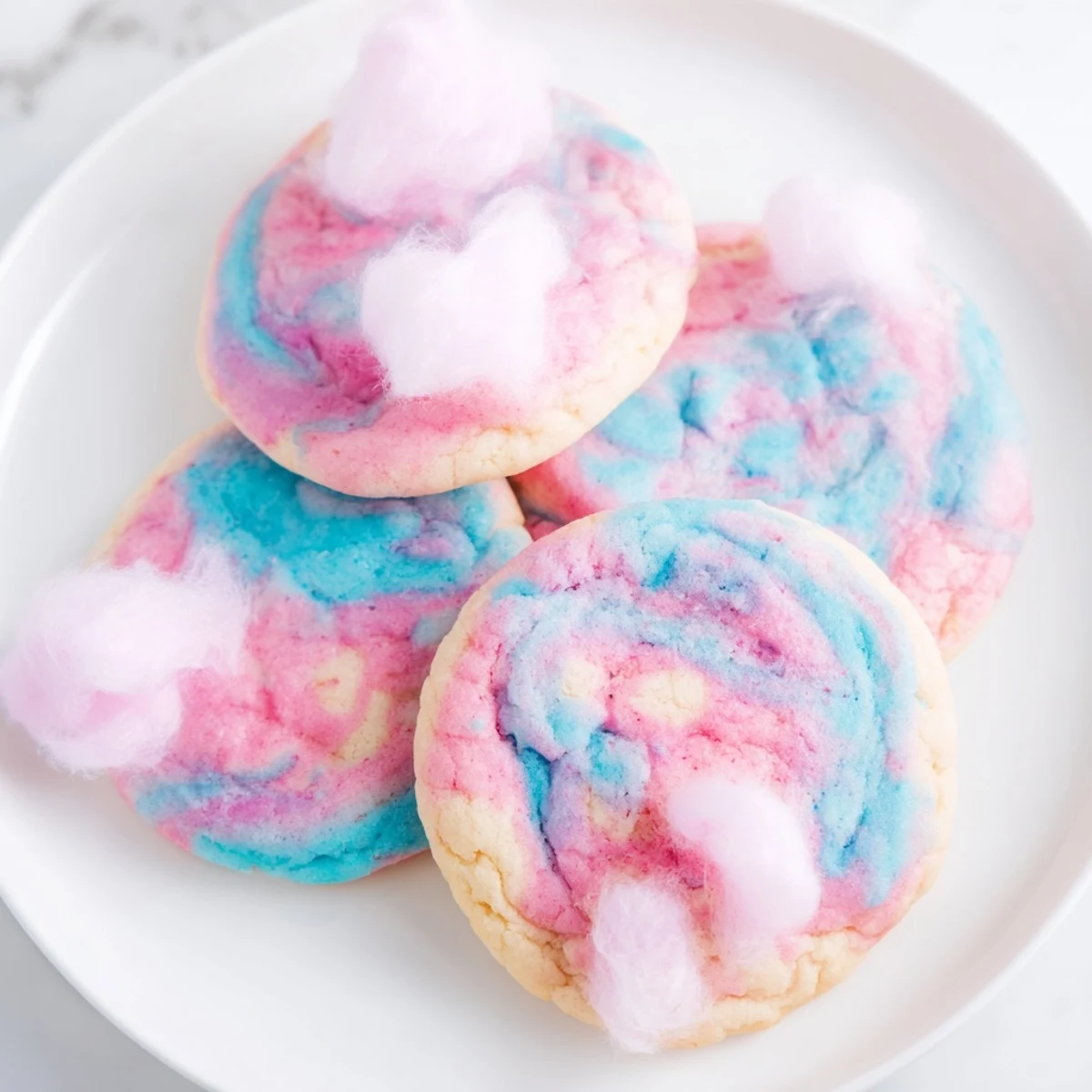 Pastel marbled cotton candy cookies topped with fluffy spun sugar garnish for a whimsical party dessert