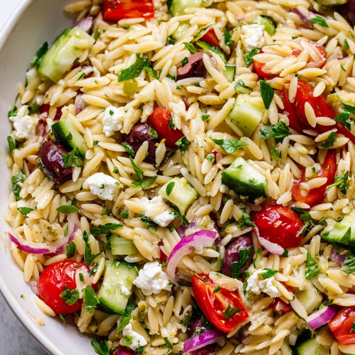 Bright Mediterranean Orzo Pasta Salad served chilled with crumbled feta and Kalamata olives