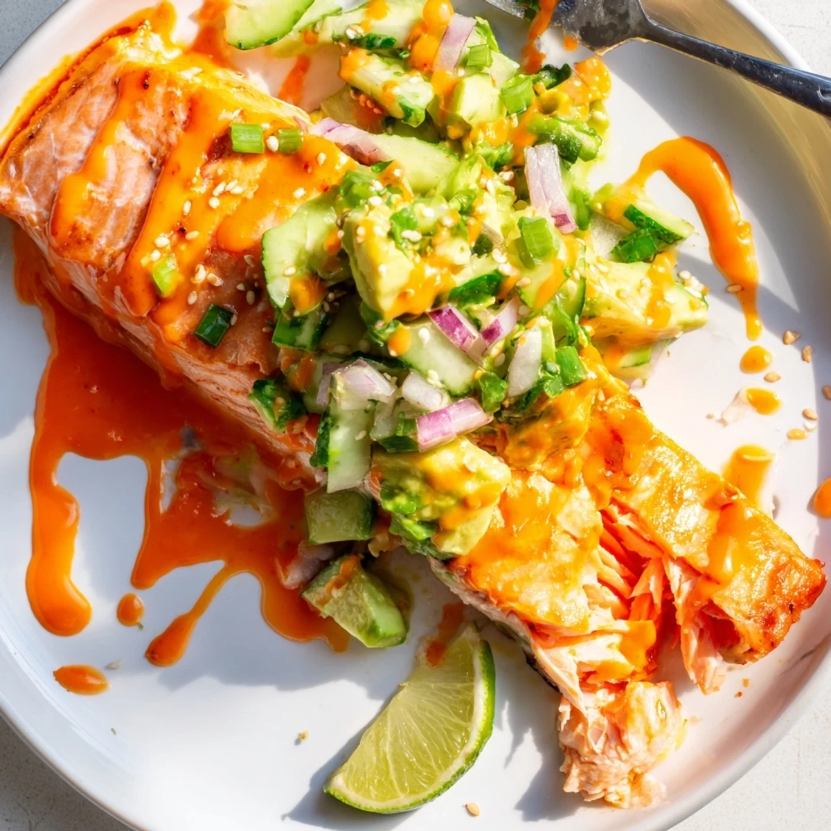 Crispy baked Bang Bang Salmon topped with creamy avocado cucumber salsa and spicy drizzled sauce