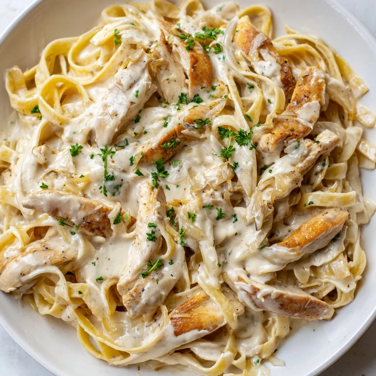 Steaming bowl of creamy garlic Parmesan chicken pasta topped with extra grated cheese