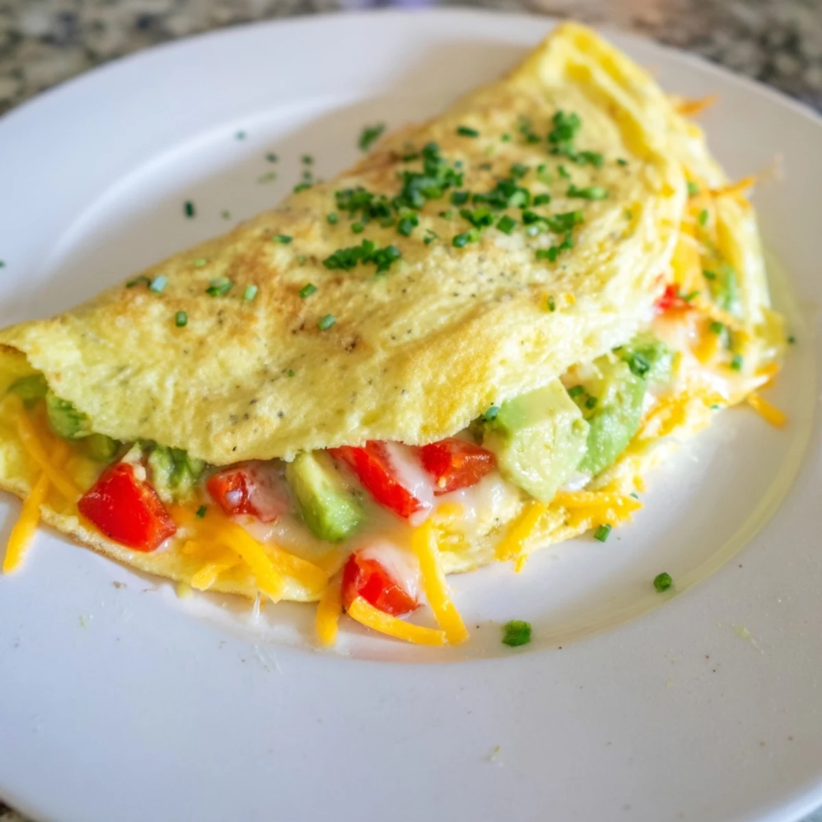 Melted cheddar and ripe avocado tucking into this creamy avocado cheesy tomato omelette