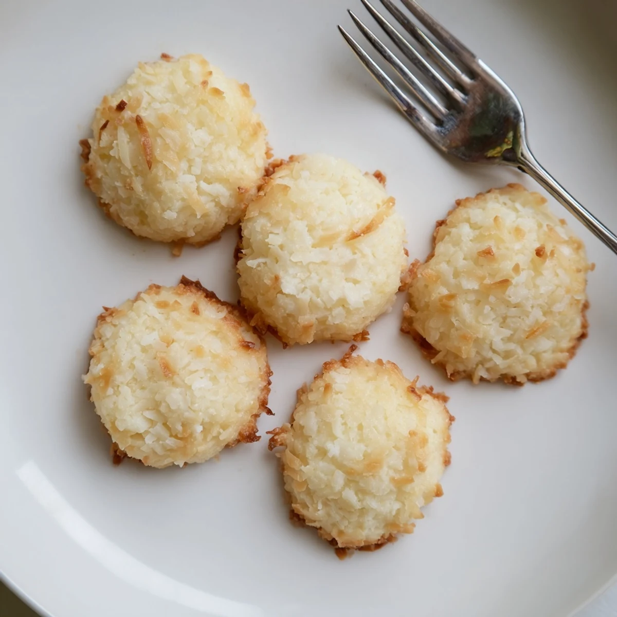 Golden soft and buttery coconut cookies cooling on a rustic wire rack