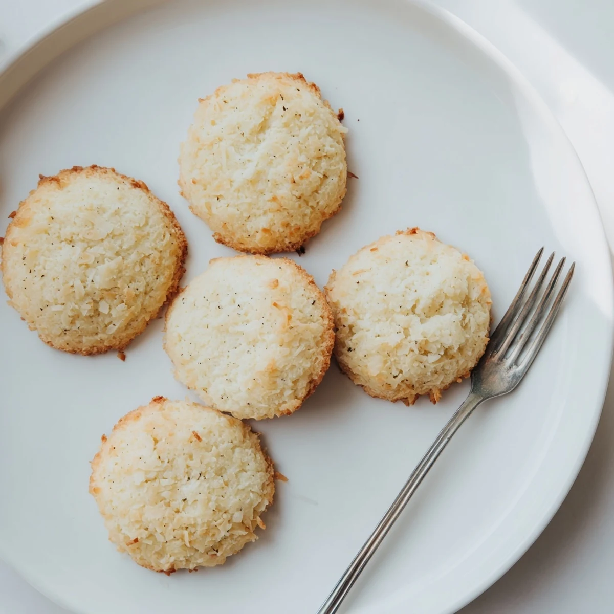Pile of soft and buttery coconut cookies served alongside a cold glass of milk