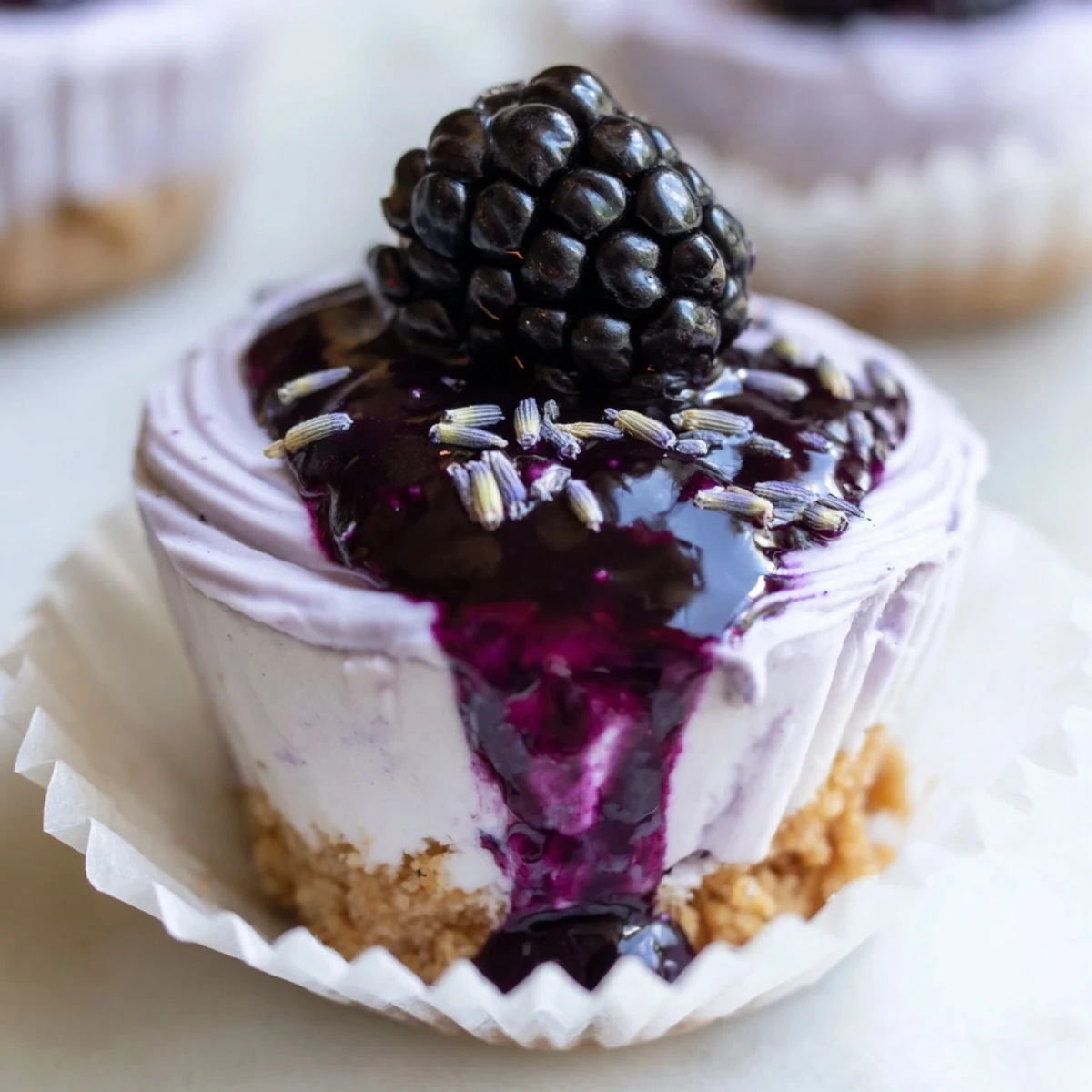 Mini Blackberry Lavender Cheesecakes topped with glossy purple blackberry sauce on a rustic wooden board
