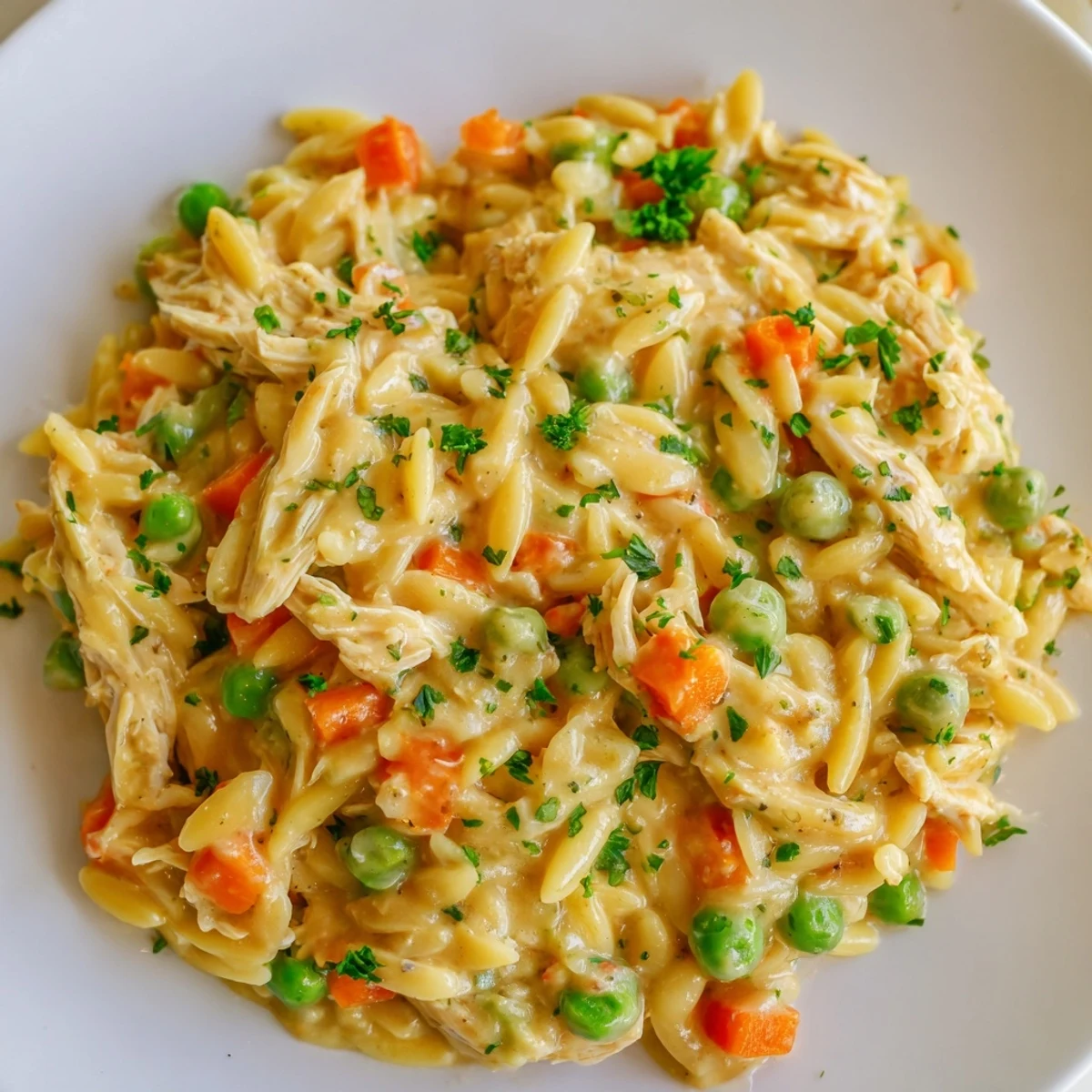 Warm creamy chicken pot pie orzo with shredded chicken bright peas and velvety gravy