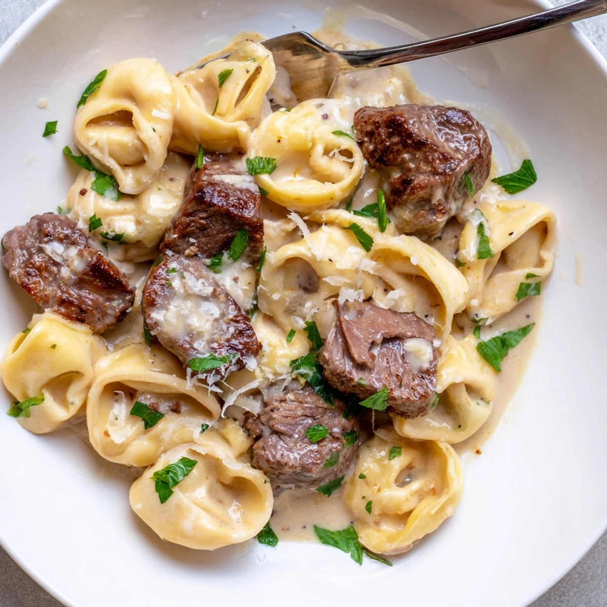 Garlic steak tortellini in creamy parmesan sauce topped with fresh parsley