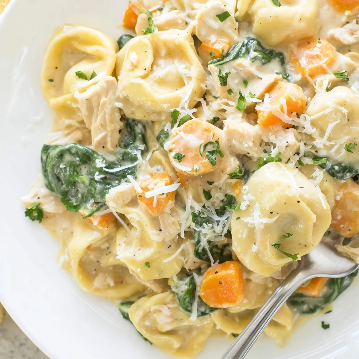 Creamy crockpot chicken tortellini in a golden sauce with spinach and Parmesan