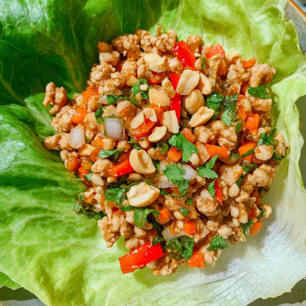 Healthy Thai chicken lettuce wraps garnished with mint, cilantro, and lime wedges