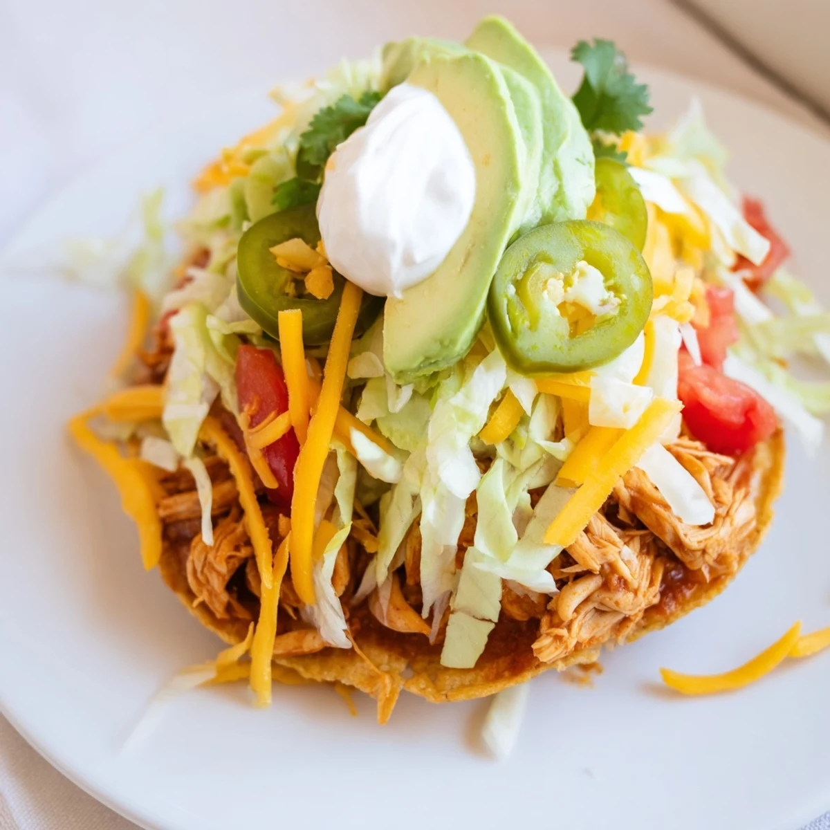Golden Chicken Tostadas topped with fresh lettuce, cheese, and creamy avocado slices  