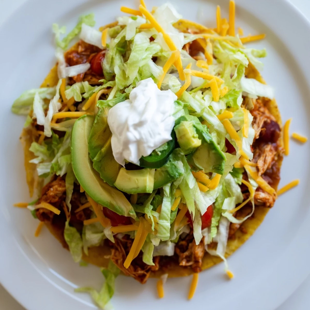 Colorful Chicken Tostadas served with sour cream, cilantro, and zesty lime wedges
