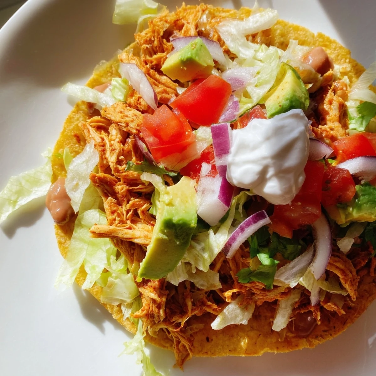 Juicy shredded chicken atop crunchy corn tortillas with avocado and cheese.  
