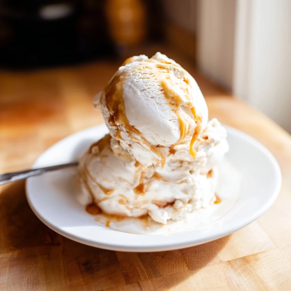 Scoop of egg-free salted caramel ice cream topped with sea salt and caramel drizzle.  