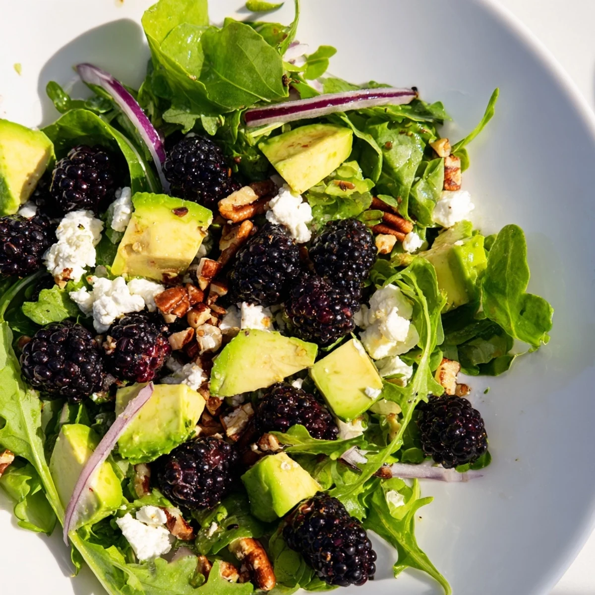 Vibrant Blackberry Avocado Salad topped with feta and pecans in a bowl.  