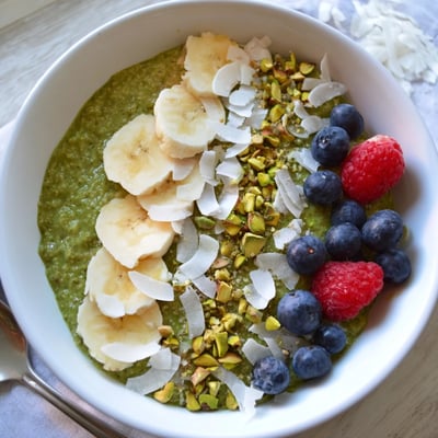 Vibrant green matcha overnight oats served with fresh berries and crunchy pistachios in a bowl